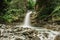 Waterfall hidden in the jungle. Flowing water. Stream in the mountains. Tropical nature. Rocks, river and trees. Long exposure