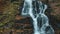 Waterfall on high hill with yellow trees on autumn day