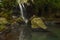 Waterfall landscape. Beautiful hidden waterfall in tropical rainforest. Foreground with big stones. Fast shutter speed. Sing Sing