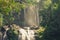 A waterfall in the middle of a jungle of the Latin American tropics with a woman at the top forming part of the scenic and