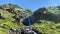 Waterfall in the mountains. Green rocky slopes of the northern Elbrus region.