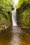 Waterfall in a narrow canyon surrounded by green foliage Sgwd Einion Gam, Waterfall Country, Wales