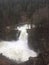 Waterfall nature power - flooded river in winter, fir tree valley