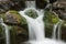 Waterfall over brown and green rocks