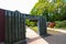 A waterfall over a stone wall with a doorway on a curved footpath in the garden with blue sky and powerful clouds