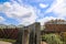 A waterfall over a stone wall with a doorway on a curved footpath in the garden with blue sky and powerful clouds