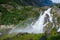 Waterfall with rainbow next to the bridge to Briksdalsbreen glacier