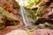 Waterfall on red stones, rocks in the woods.