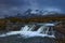 Waterfall on River Sligachan on the Isle of Skye Scotland with large mountains of the Cuillin Range in the distance with snow in