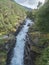 Waterfall Slettafossen at Verma with deep narrow Rauma river canyon at Romsdalen valley with rocks and green forest. Blue sky