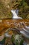 Waterfall with smooth water and orange leaves in the fall