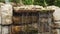 Waterfall of stone with moss in the park. The water flows down in streams and drops and falls down.