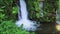 Waterfall Among Tropical Plants And Green Leaves In Bali, Indonesia. Wonderful Mountain Stream With Splashing Water Flowing From