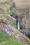 A waterfall tumbles through a narrow rocky gully in Scotland