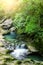 Waterfalls on the mountain river. Summer landscape. Rays of the sun through foliage