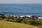 Waterfront lookout on hill with idyllic and amazing seaside landscape of shrubs and grass, jagged coast with rocks, ocean horizon