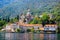 Waterfront of small town Prcanj along Bay of Kotor, Montenegro. View of Birth of Our Lady Church, coastal villas, gardens and moun
