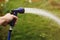 Watering green garden with outdoor hose. hand with hose sprinkle watering plants in the garden. watering lawn or plants