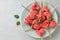 Watermelon hearts on sticks with mint in blue plate on gray stone background.