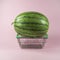 Watermelon on miniature steel shopping basket. On trendy pastel pink background