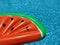 Watermelon pool float, part of ring floating in a refreshing blue swimming pool