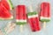 Watermelon popsicles with fresh melon slices on white marble