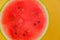 Watermelon pulp close-up. Watermelon cut on a yellow background. ripe red watermelon half. Appetizing summer fruits.