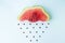 watermelon rain, slice of watermelon in the shape of a cloud with seeds as raindrops. autumn or summer concept. flay lay