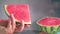 Watermelon rotating in a person\'s hand, a person cutting the watermelon with a wide knife