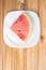 Watermelon in slice on a white crockery on wood, top view