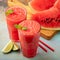 Watermelon slushie with lime, summer refreshing drink in tall glasses on a blue rusty background