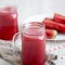 Watermelon smoothie in glass jars with fresh slices of water melon over white wooden sbackground, side view. Close-up