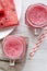 Watermelon smoothie in glass jars with fresh slices of water melon, overhead view. White wooden background. Flat lay