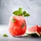Watermelon sorbet cocktail with crushed ice and mint leaf on light grey background, close up. Freshly blended iced watermelon