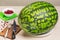 Watermelon on a white plate, red berry cranberries on wooden background, knife, fork , green cloth Board for preparing