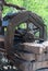 Watermill wooden water wheel mill, stone bricks wall, water flows from the wheel, on the background of green trees