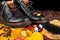 Waterproof Black boots on wooden background with autumn leaves polishing equipment, brush and polish cream.