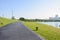 Waterside blacktopped pedestrian way on grassy lawn in sunny summer morning