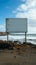 Waterside emptiness Billboard against sandy shore, overlooking the vast sea