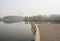 Waterside fenced and planked platform in sunny foggy winter