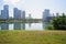 Waterside grassy lawn in summer morning with modern city across lake