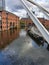 Waterway canal area with a modern bridge in the foreground and lined narrowboats in the distance in Castlefield district,