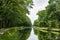 Waterways in Belgium, manmade canal with oak trees alley