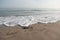 Wave approaching pebble on the beach sand