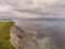 Wave breaker and pier, Spiddal, county Galway, Ireland, Burren in the background. Cloudy sky, Atlantic ocean