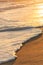 Wave breaking on the beach forming white foam