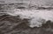 Wave breaking early on a stormy day at high tide on Ramsgate West Cliff beach in black and white