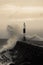 Wave breaking on jetty and beacon during storm at Aberystwyth in Wales.