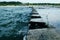 Wave breaking on jetty with blue metall bollards in Michigan