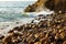 Wave breaking on rocks at shoreline with sunrise